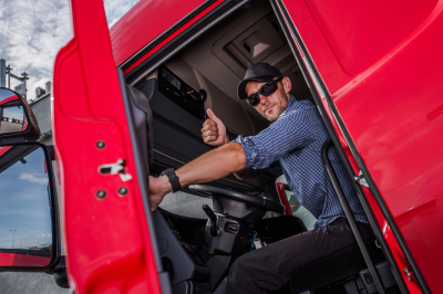 a semi truck driver giving a thumbs up out of his cab. native american logistics
